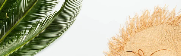 Vista dall'alto di foglie di palma verde vicino cappello di paglia su sfondo bianco, colpo panoramico — Foto stock