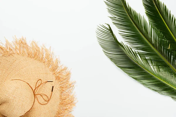 Vista dall'alto di foglie di palma verde vicino cappello di paglia su sfondo bianco — Foto stock