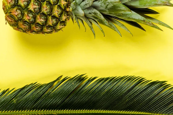 Draufsicht auf grünes Palmblatt und reife Ananas auf gelbem Hintergrund — Stockfoto