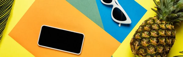 Top view of sunglasses, smartphone and ripe pineapple on colorful background, panoramic shot — Stock Photo