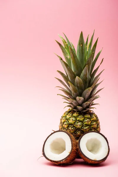 Ripe pineapple and fresh coconut halves on pink background — Stock Photo