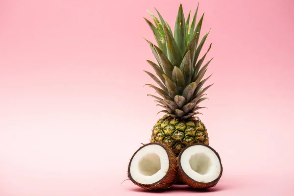 Reife Ananas und frische Kokosnusshälften auf rosa Hintergrund — Stockfoto