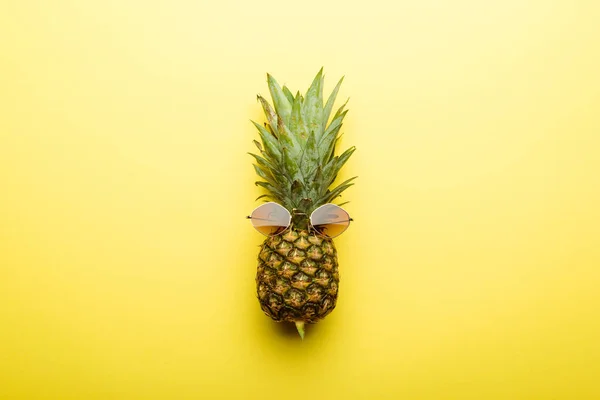Top view of ripe pineapple in sunglasses on yellow background — Stock Photo