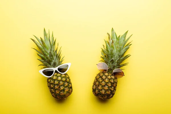 Vue du dessus des ananas mûrs dans les lunettes de soleil sur fond jaune — Photo de stock