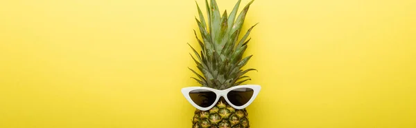 Top view of ripe pineapple in sunglasses on yellow background, panoramic shot — Stock Photo