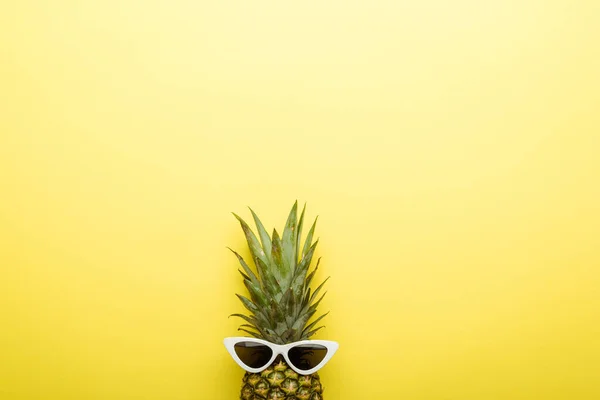 Top view of ripe pineapple in sunglasses on yellow background — Stock Photo