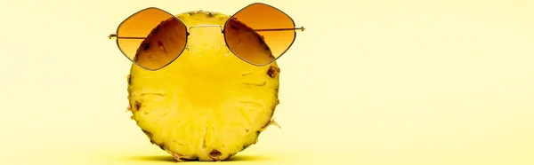 Delicious sweet cut pineapple in sunglasses on yellow background, panoramic shot — Stock Photo