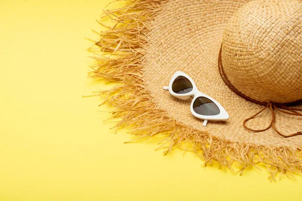 Sombrero de paja y gafas de sol con estilo sobre fondo amarillo - foto de stock