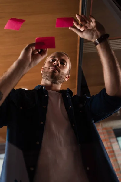 Low angle view of handsome businessman looking at sticky note — Stock Photo