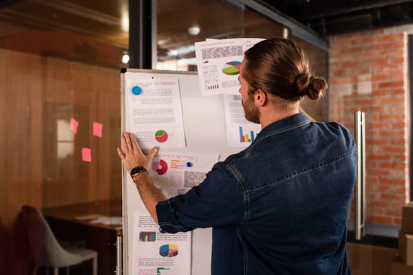 Bearded businessman touching charts and graphs on flipchart — Stock Photo