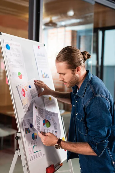 Bell'uomo d'affari che guarda grafici e grafici in ufficio — Foto stock
