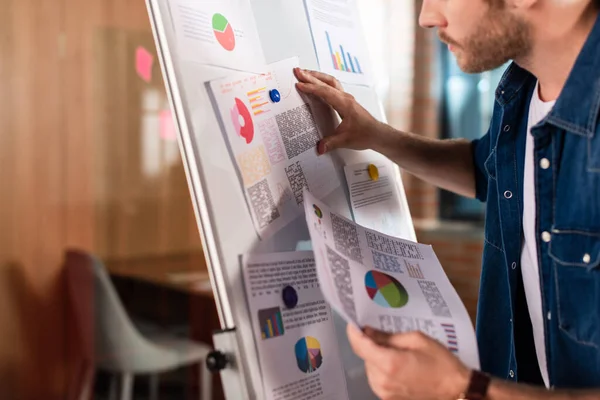 Cropped view of bearded businessman touching charts and graphs on flipchart — Stock Photo