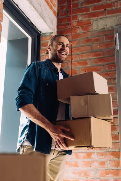 Foco seletivo de empresário feliz segurando caixas de papelão enquanto se move no novo escritório — Fotografia de Stock