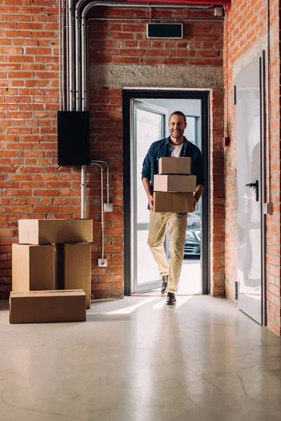 Счастливый бизнесмен держит картонные коробки во время переезда в новый офис — стоковое фото