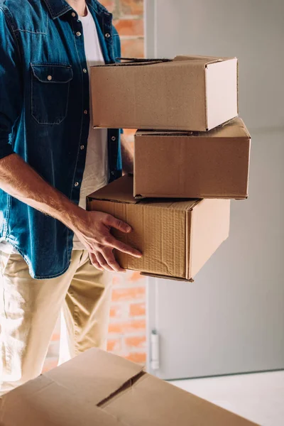 Vista parcial del hombre sosteniendo cajas de cartón mientras se mueve en una nueva oficina - foto de stock