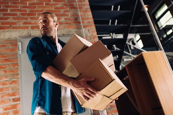 Low angle view of man holding carton boxes while moving in new office — Stock Photo