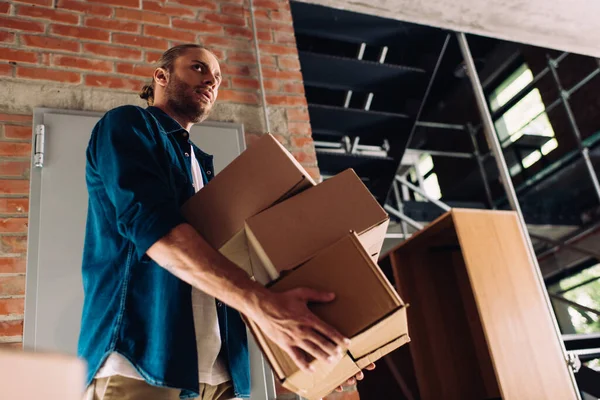 Низкоугольный вид человека, держащего коробки во время переезда в новый офис — стоковое фото