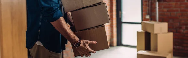 Panoramic crop of businessman holding boxes and moving in new office — Stock Photo