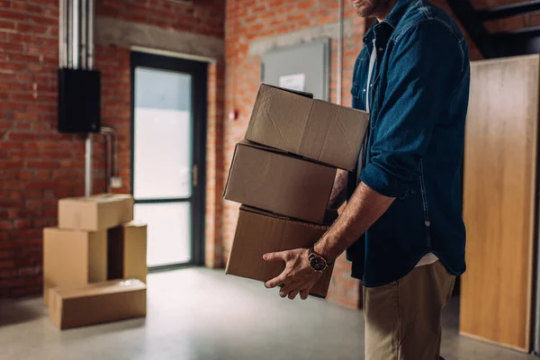 Cropped view of businessman holding boxes and moving in new office — Stock Photo