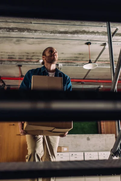 Selektiver Fokus glücklicher Geschäftsleute, die Kisten halten, während sie im Büro auf Treppen gehen — Stockfoto