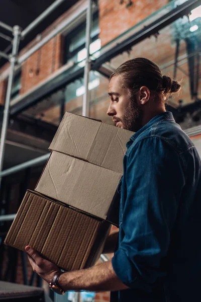 Selective focus of bearded businessman looking at carton boxes in new office — Stock Photo