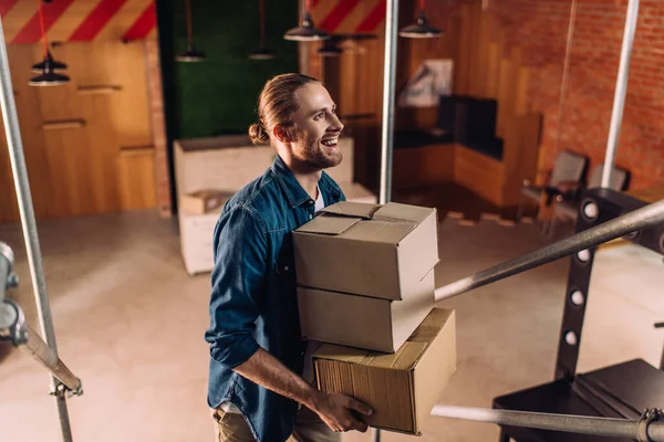 Sonriente hombre de negocios sosteniendo cajas en nueva oficina - foto de stock