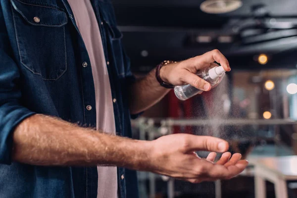 Cropped view of man spraying sanitizer on hand in office — Stock Photo