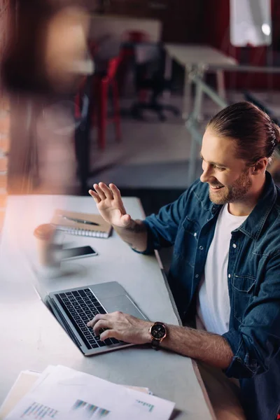 Selektiver Fokus eines glücklichen Geschäftsmannes, der während eines Videoanrufs winkt — Stockfoto