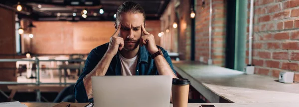 Panoramic crop of pensive businessman looking at laptop in office — Stock Photo