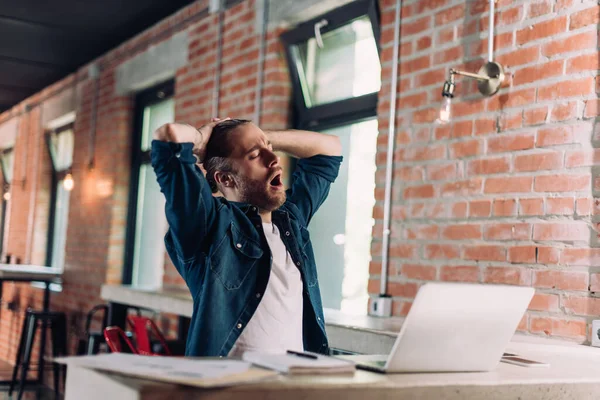 Selektiver Fokus müder Geschäftsleute, die neben Laptop im Büro gähnen — Stockfoto