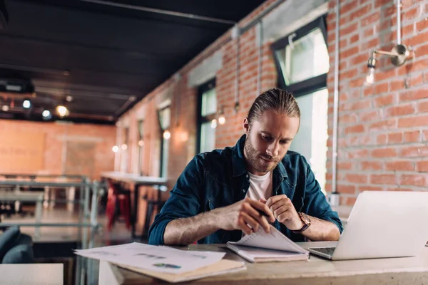 Selective focus of concentrated businessman looking at notebook near laptop — Stock Photo