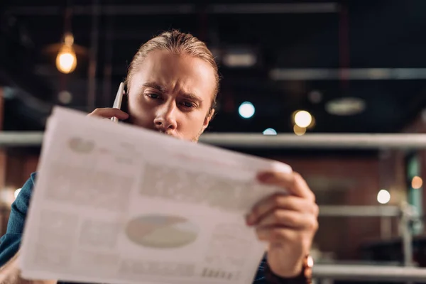 Selective focus of businessman talking on smartphone while looking at charts and graphs — Stock Photo