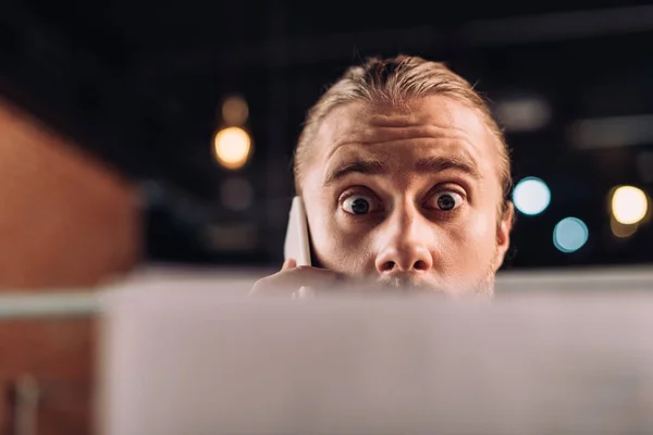 Selective focus of shocked businessman talking on smartphone and holding charts and graphs — Stock Photo