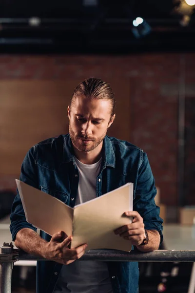 Guapo hombre de negocios que sostiene la carpeta en la oficina moderna - foto de stock