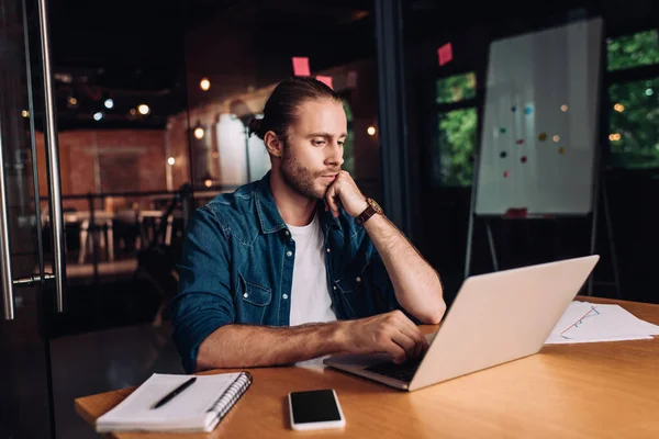 Uomo d'affari barbuto utilizzando laptop vicino notebook e smartphone con schermo bianco — Foto stock