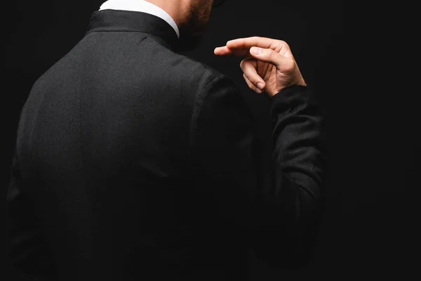 Cropped view of priest gesturing isolated on black — Stock Photo