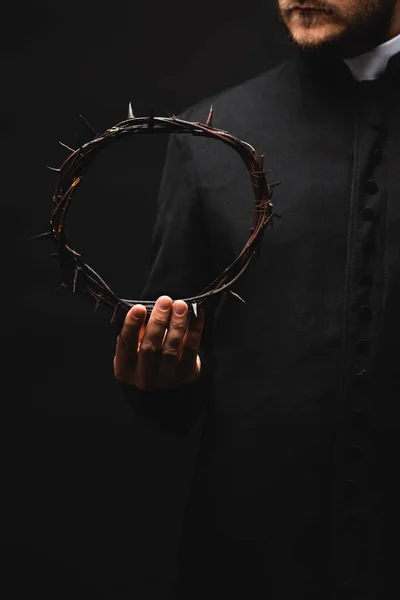 Cropped view of priest holding wreath with spikes in hand isolated on black — Stock Photo