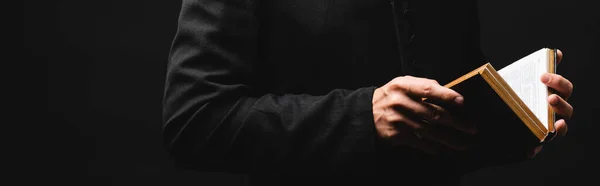 Intestazione del sito web del sacerdote che tiene santa bibbia in mani isolate su nero — Foto stock