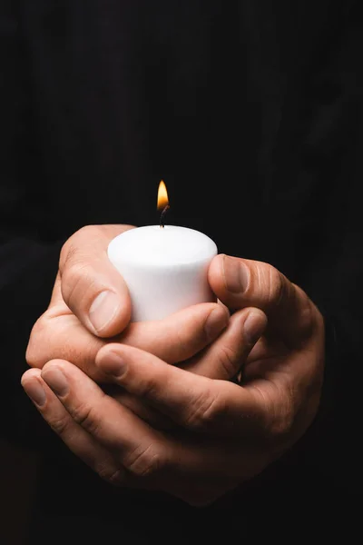 Cropped view of priest holding burning candle isolated on black — Stock Photo