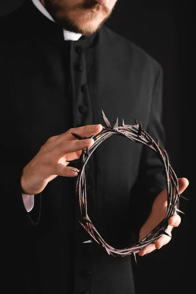 Cropped view of bearded priest holding sharp wreath with spikes isolated on black — Stock Photo