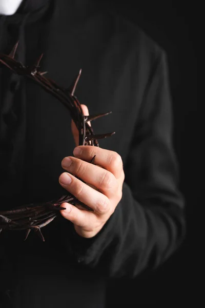 Selective focus of priest holding sharp wreath with spikes isolated on black — Stock Photo