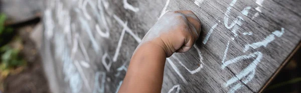 Panoramic crop of african american child writing on chalkboard — Stock Photo