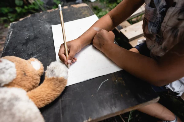 Vue partielle de l'enfant afro-américain tenant un crayon tout en écrivant sur papier — Photo de stock