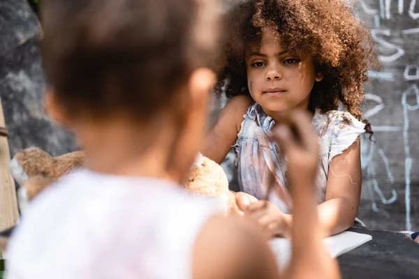 Selective focus of curly and poor african american child looking at kid — Stock Photo