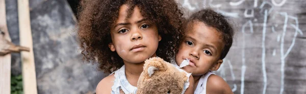 Orientación panorámica de los niños afroamericanos pobres mirando la cámara - foto de stock