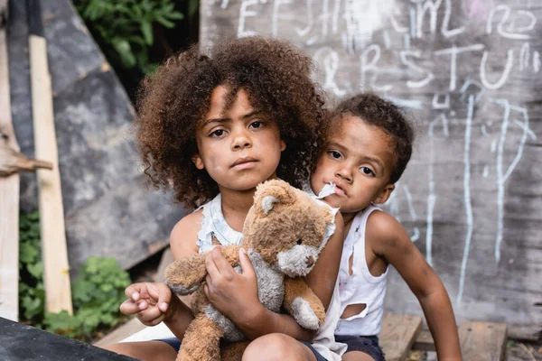 Pobres afro-americanos crianças com sujo ursinho de pelúcia olhando para câmera — Fotografia de Stock