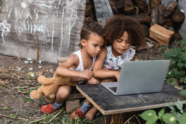 Selective focus of poor african american kids using laptop outside — Stock Photo