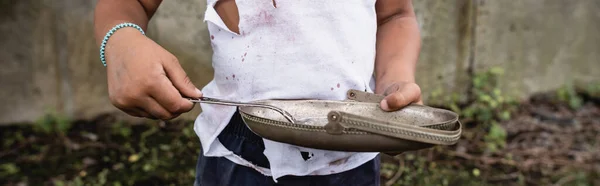 Panoramaorientierung eines afrikanisch-amerikanischen Jungen in schmutziger Kleidung mit Metallteller und Löffel auf der Stadtstraße — Stockfoto