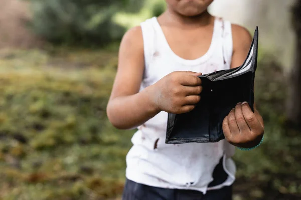 Vista ritagliata del povero ragazzo americano arfican in possesso di portafoglio sulla strada urbana — Foto stock