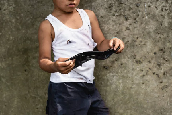 Vista recortada de mendigo afroamericano niño sosteniendo billetera cerca de muro de hormigón en la calle urbana - foto de stock